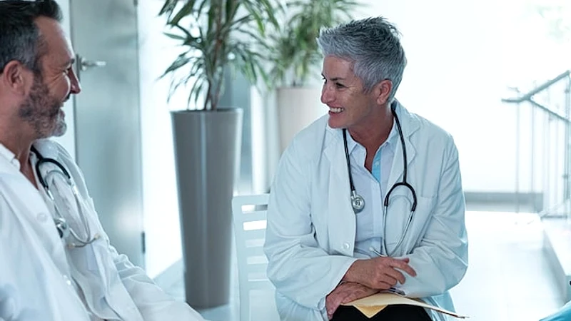 Diverse male and female doctors sitting in hospital corridor and having discussion