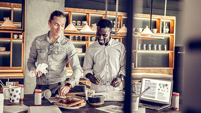 Good mood. Kind young man pressing lips while wiping his table