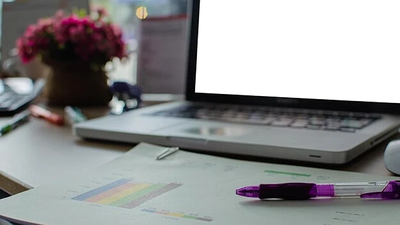 Close-up of laptop with documents on desk in office