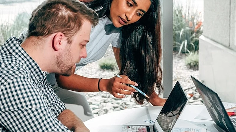 a man and a woman are looking at a laptop