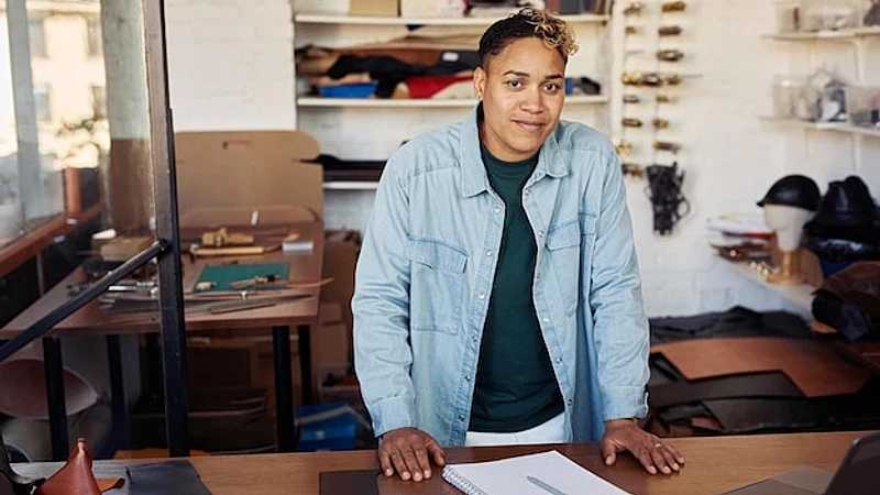 Portrait of fmodern young woman smiling at camera while posing in leatherworking workshop female sma