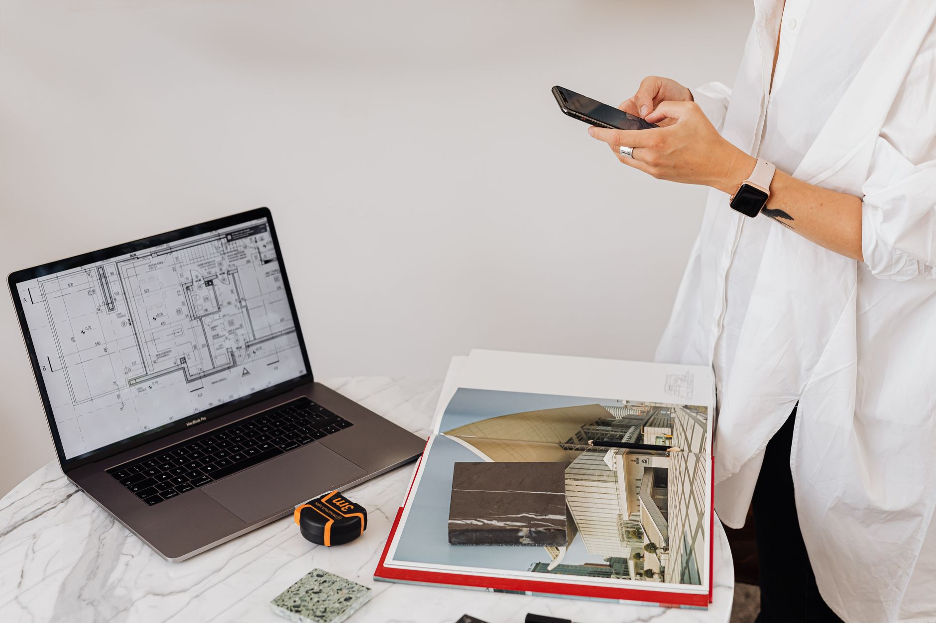 Stylish person with a smartphone at work desk with laptop and charts.