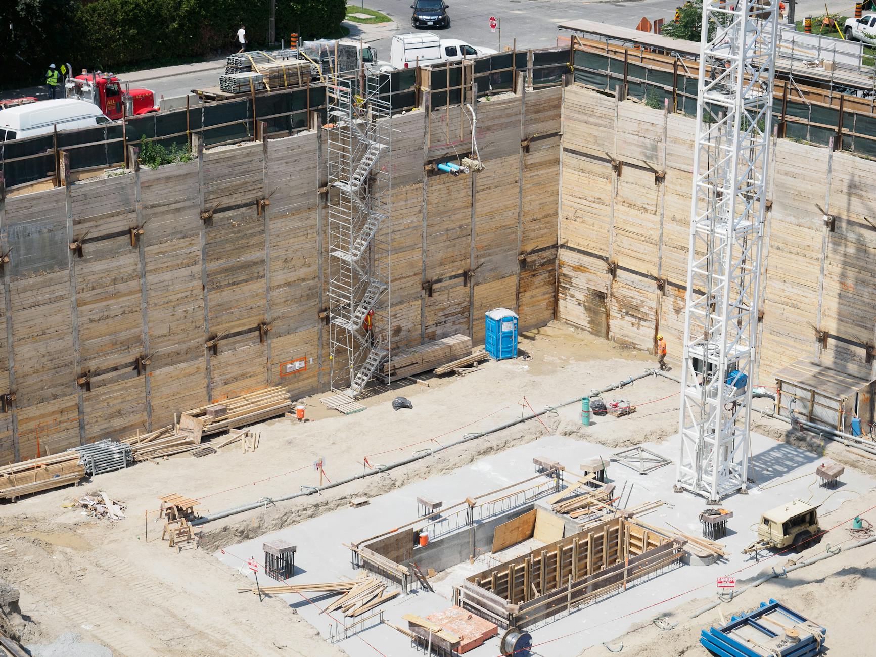 An aerial view of a construction site with workers and equipment under sunlight.