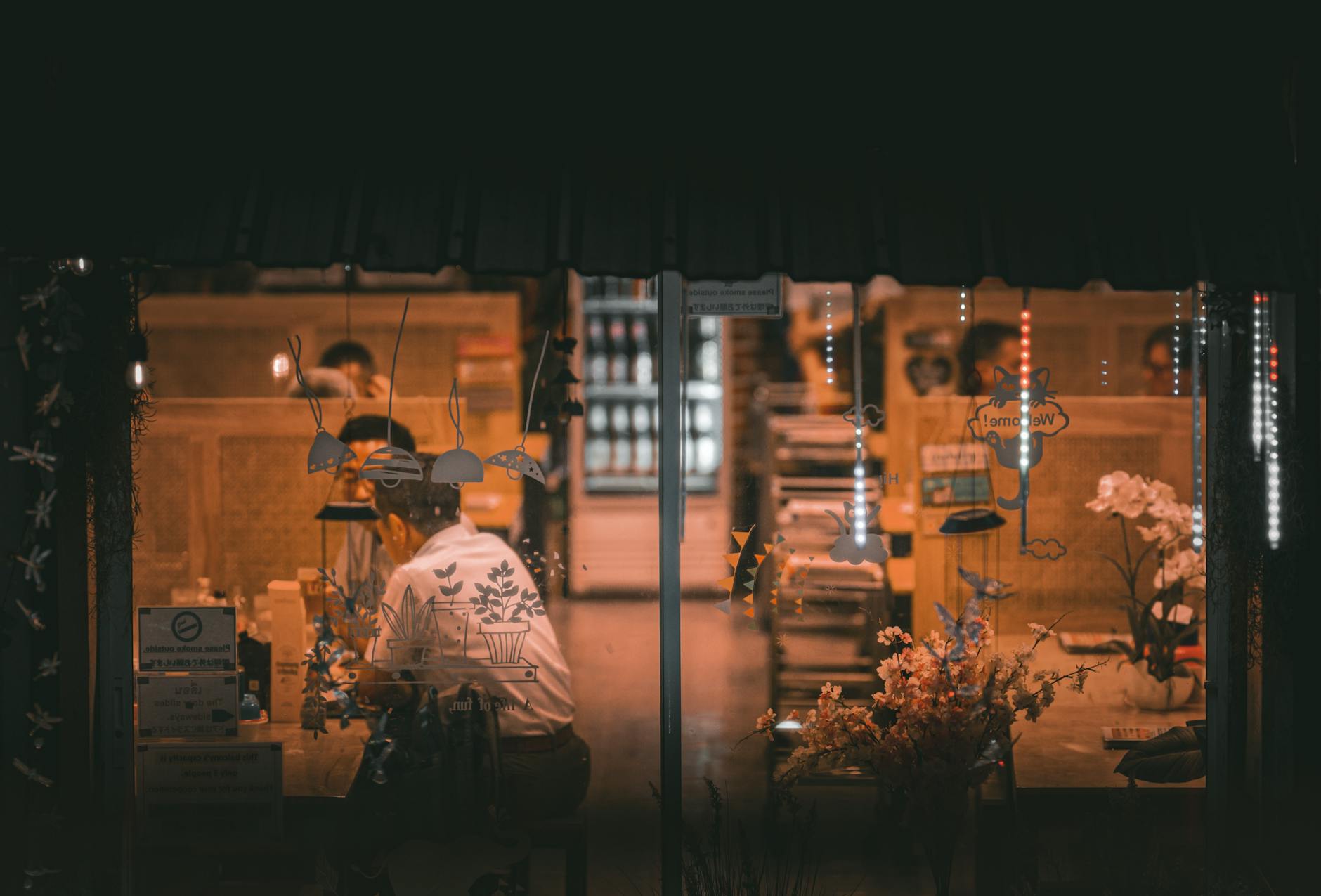 Warm ambient lighting inside a café in Bangkok, Thailand, with people dining and floral decor.