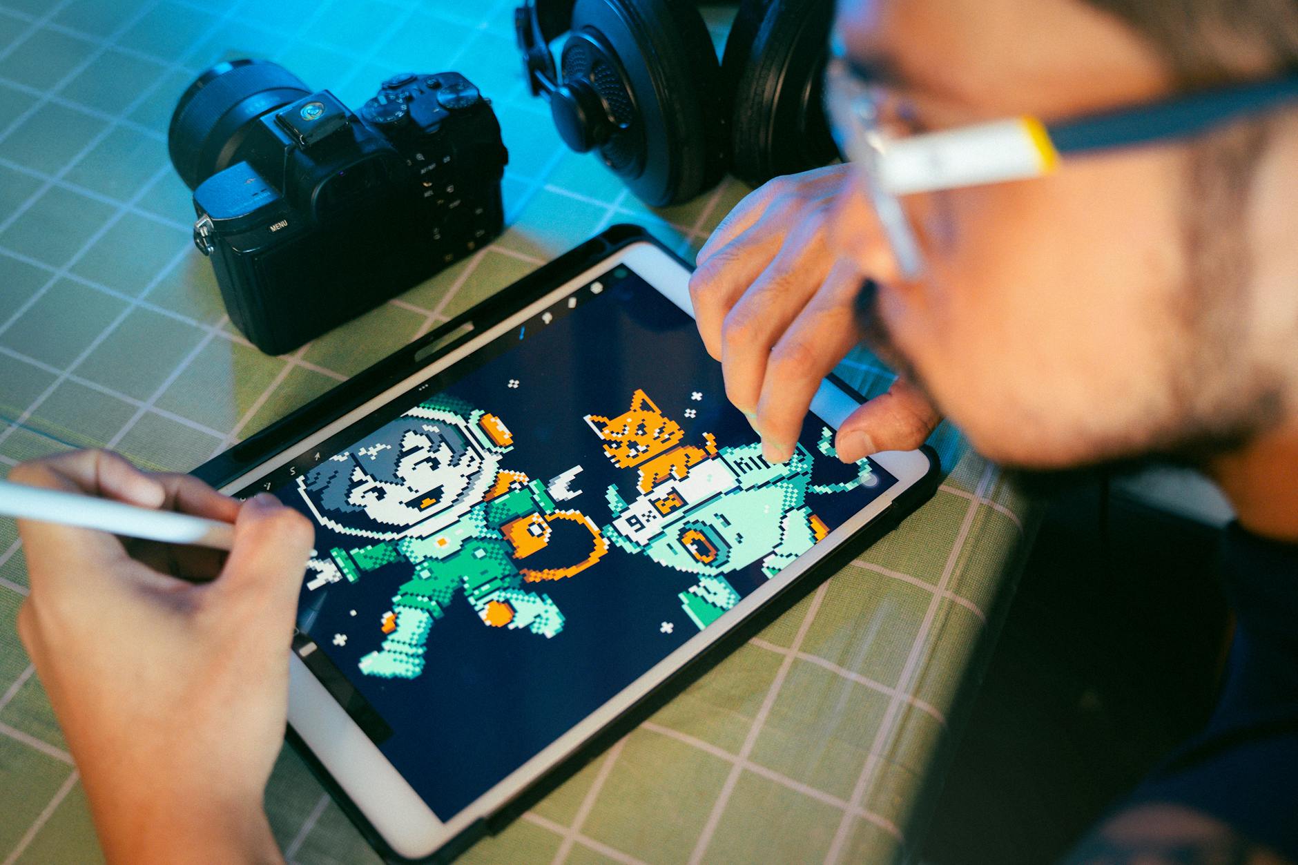 Person drawing digital art on a tablet using a stylus next to camera and headphones.