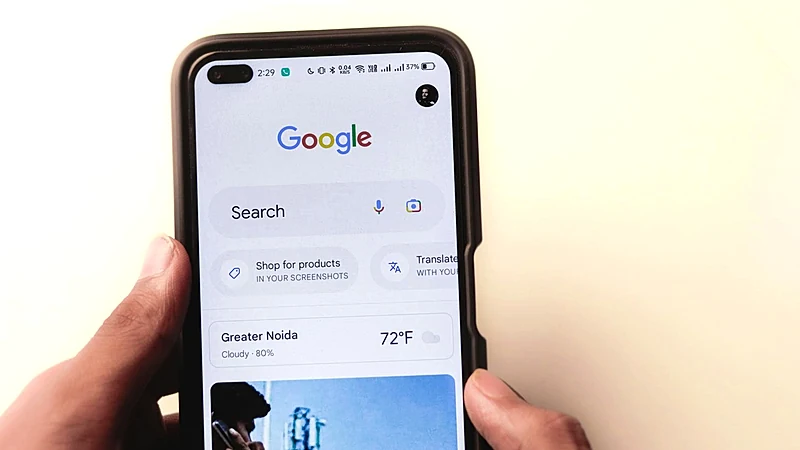A close-up of a hand holding a smartphone with Google search displayed on the screen.