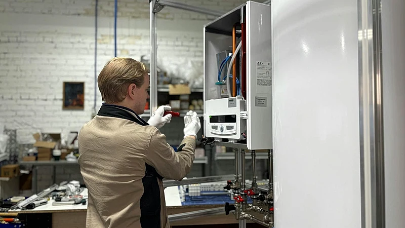 Technician inspects and repairs a heating system in an industrial workshop setting.