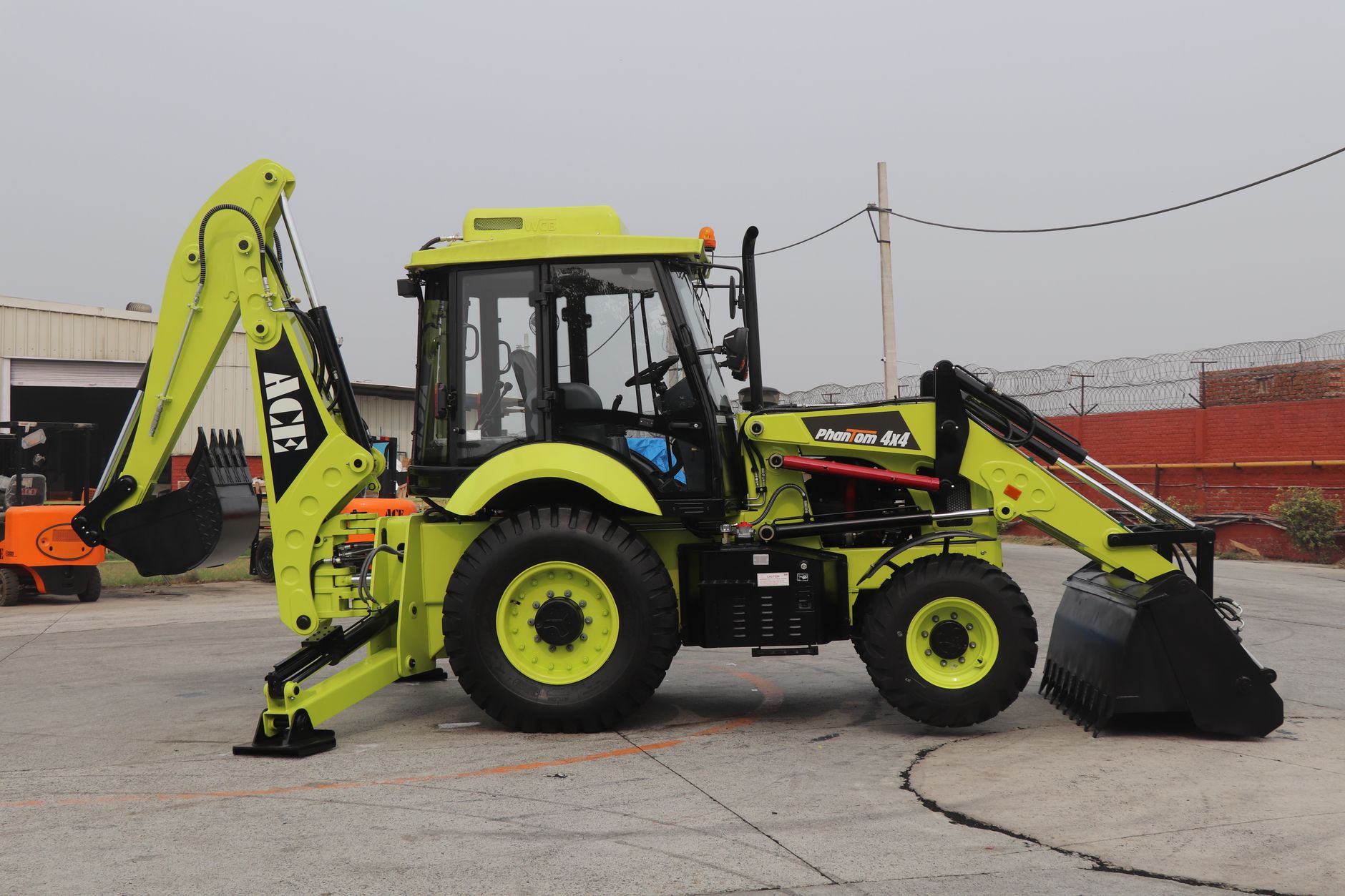 Yellow ACE Phantom 4x4 backhoe loader at an industrial site in Faridabad, India.