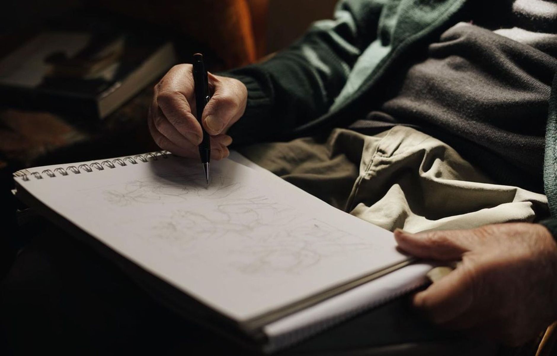 A person sketching with a pen on a sketchpad, highlighting creative focus.