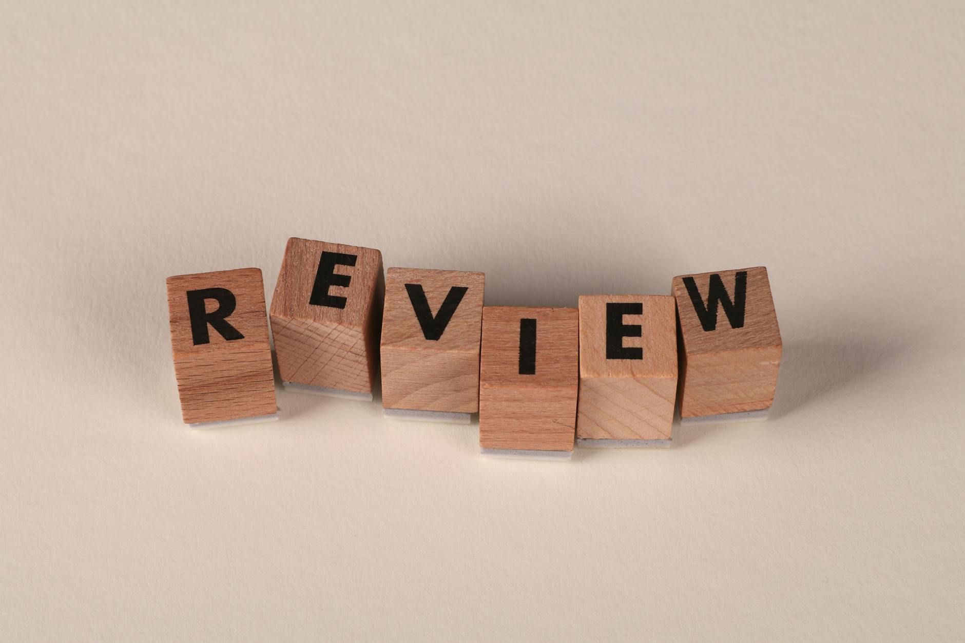 Wooden blocks with letters forming the word 'Review' on a soft pastel background.