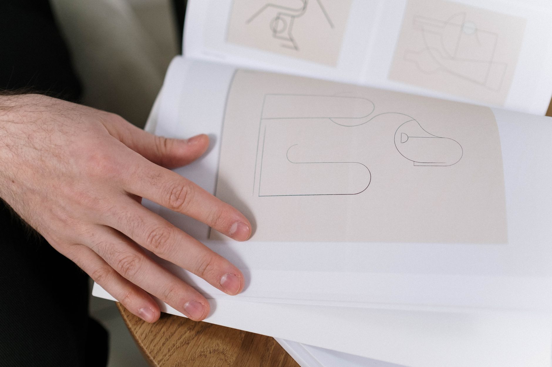 Close-up of a hand flipping through a minimalist abstract art book with geometric designs.