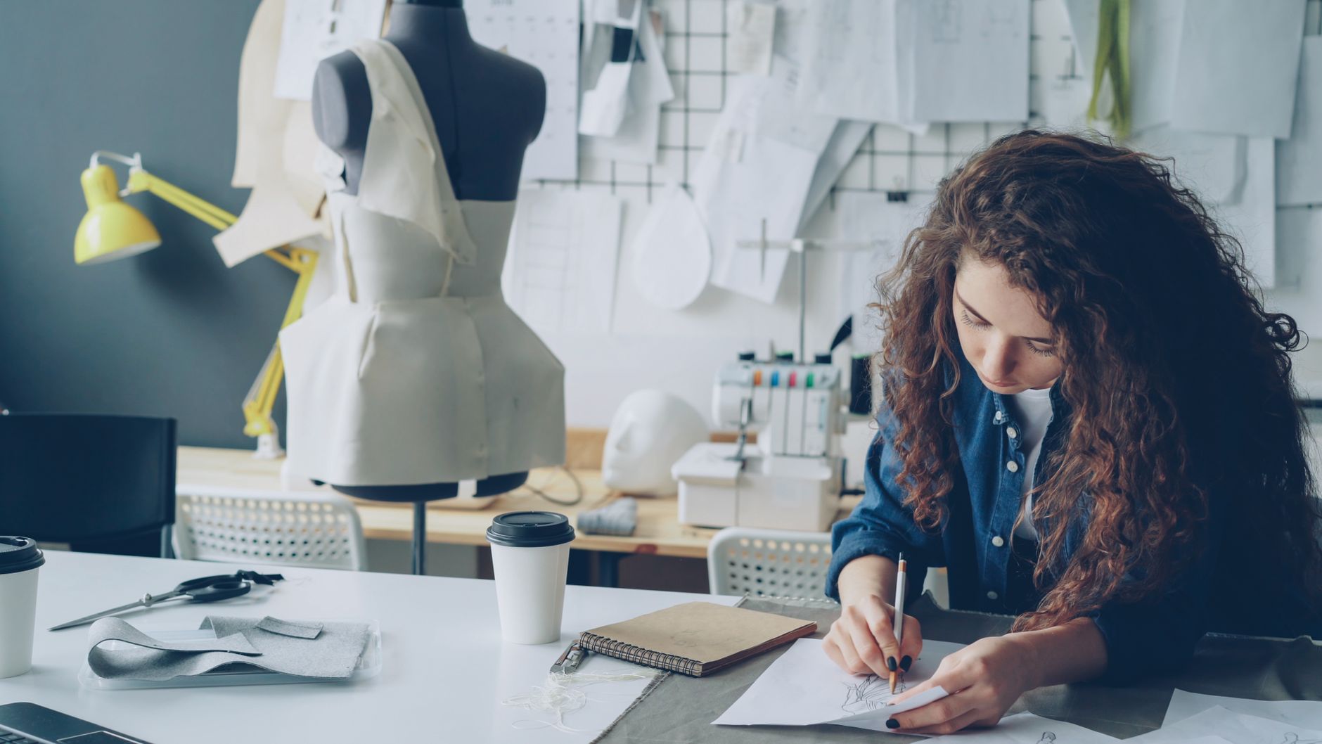 Young female fashion designer creating sketches in a modern studio.