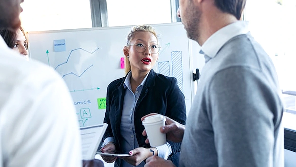 Shot of elegant young businesswoman talking with colleagues in the meeting on coworking space.