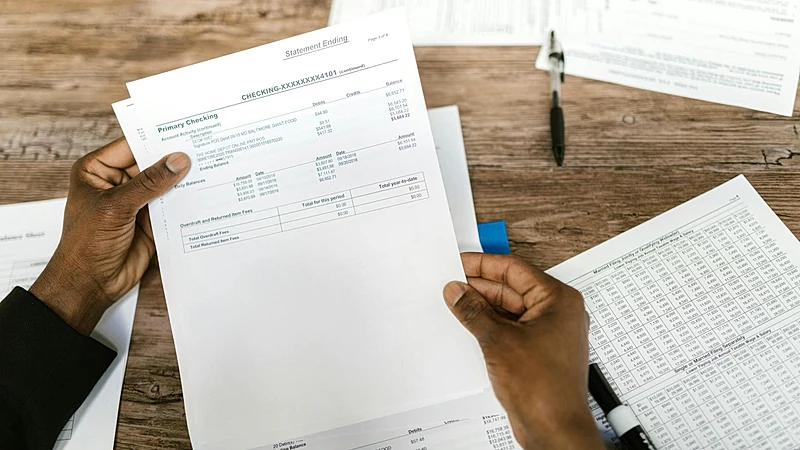 Hands holding financial papers for tax preparation and analysis.