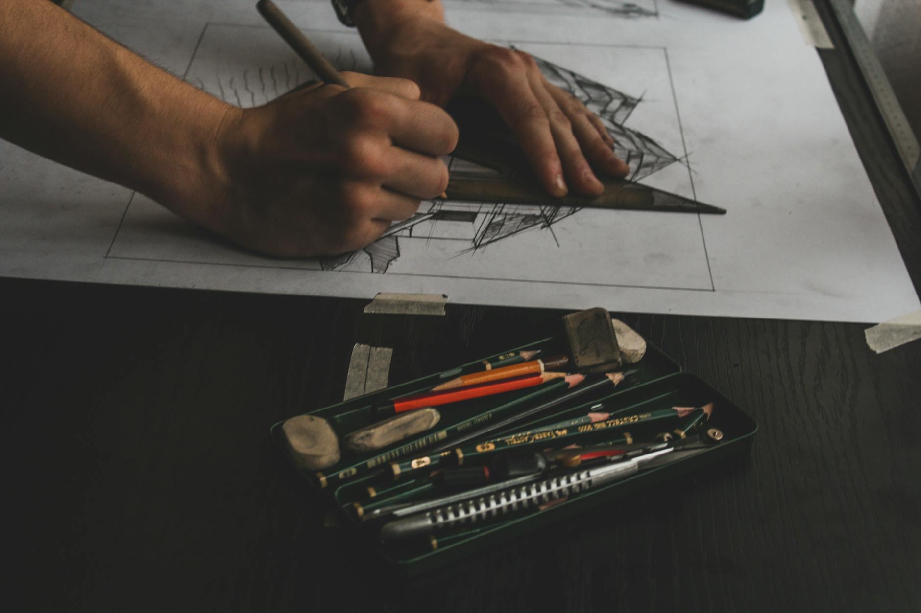 Hands working on a detailed sketch with pencils and erasers, showcasing artistic focus.