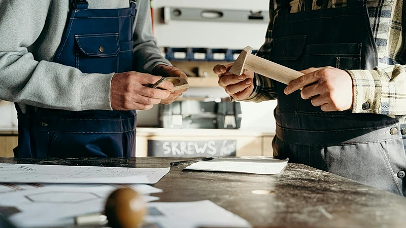 Two craftsmen working on a woodworking project in a well-lit workshop.