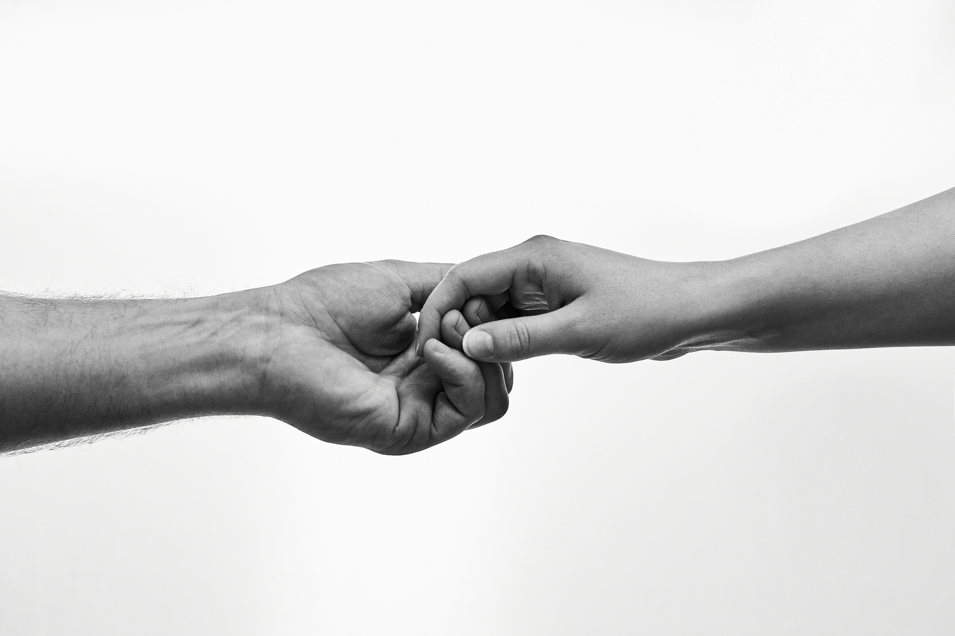 Black and white photo of two hands connecting, symbolizing unity and support.