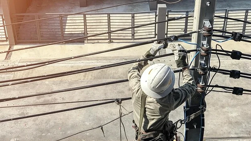 Rear view of electrician repairing power lines