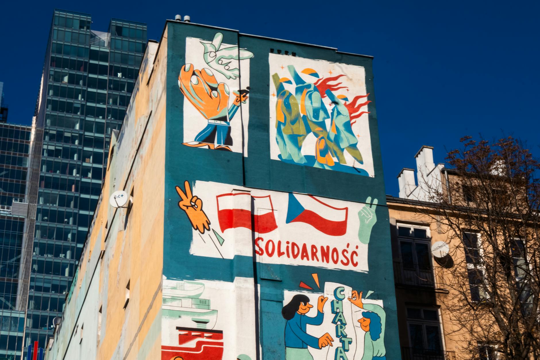 Vibrant street mural featuring flags and art on an urban building facade.